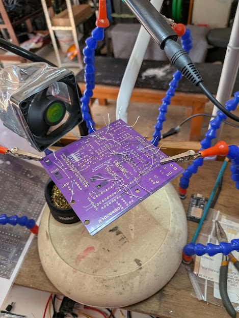 Speeduino v0.4.4b purple PCB held in helping hands tool during soldering, wires attached to test points